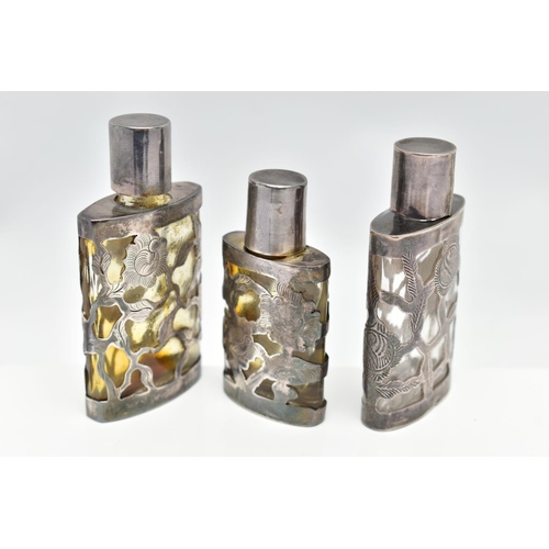 44 - THREE MEXICAN SCENT BOTTLES, the glass bottles with pierced foliate designed cases, all stamped ster... 