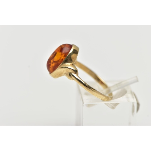 47 - A 9CT YELLOW GOLD AMBER CABOCHON RNIG, collet set with an oval cut amber cabochon, twist detail to t... 