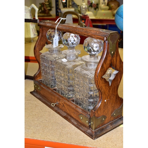 471 - AN EDWARDIAN TANTULUS, with brass mounts, containing three square cut crystal decanters each with a ... 