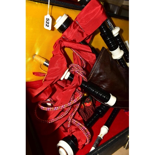 522 - A SET OF MODERN BAGPIPES with ebonised wood and plastic rings, red ribbon and tartan covering a leat... 