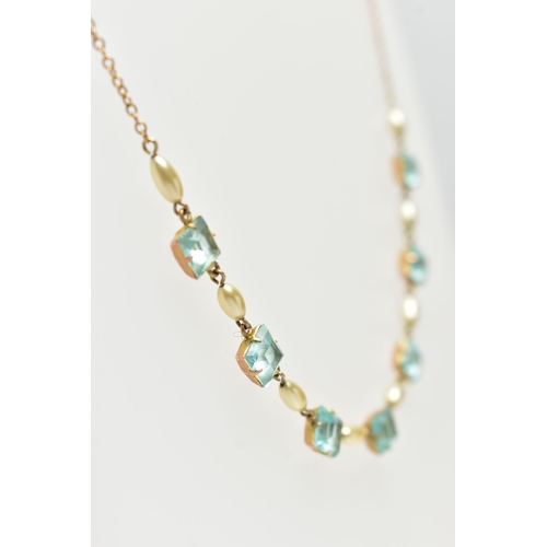 61 - A MID 20TH CENTURY YELLOW METAL NECKLACE, set with seven pale blue square cut pastes, each claw set ... 