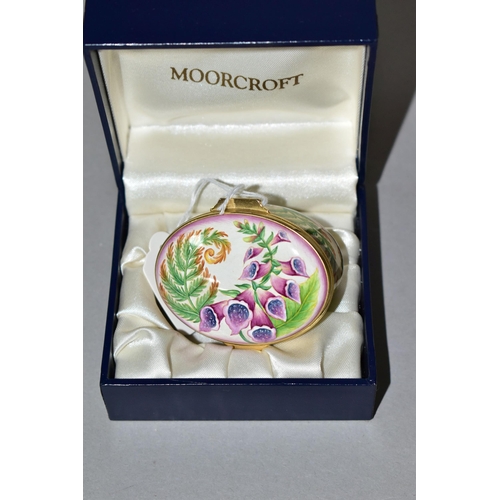 355 - A BOXED MOORCROFT ENAMEL TRINKET BOX, of oval form, decorated in the 'Foxgloves' pattern, with fern ... 