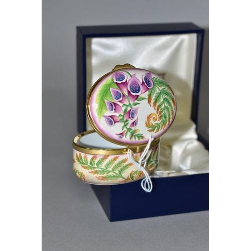 355 - A BOXED MOORCROFT ENAMEL TRINKET BOX, of oval form, decorated in the 'Foxgloves' pattern, with fern ... 