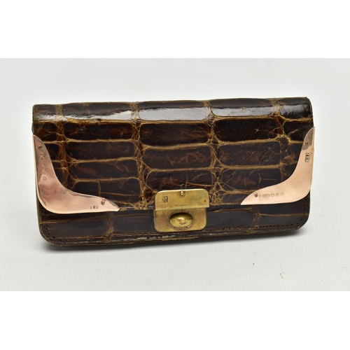 104 - AN EARLY 20TH CENTURY CROCODILE SKIN PURSE, mounted with two 9ct rose gold hard wear corners to the ... 