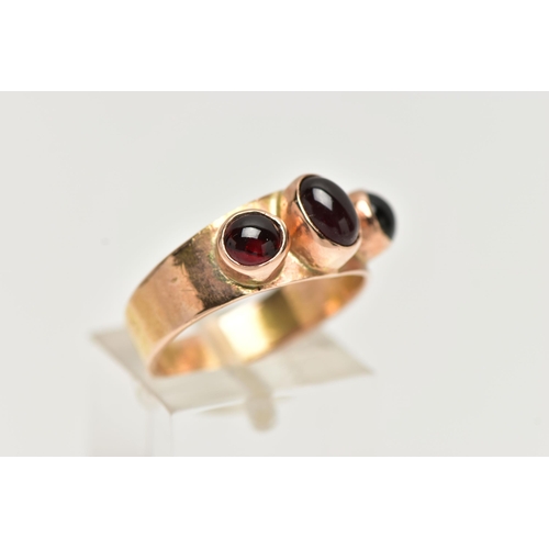 80 - A GARNET THREE STONE RING, set with a principal oval garnet cabochon, and two circular garnet caboch... 