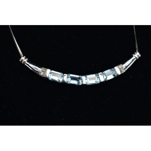 29 - A 9CT GOLD, TOPAZ NECKLACE, a solid white gold crecent shaped bar, set with four emerald cut blue to... 