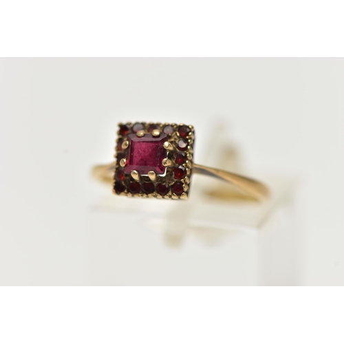 12 - A 9CT GOLD GEMSET RING, a square cut garnet, set with a surround of sixteen circular cut garnets, le... 