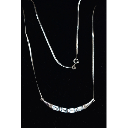 29 - A 9CT GOLD, TOPAZ NECKLACE, a solid white gold crecent shaped bar, set with four emerald cut blue to... 