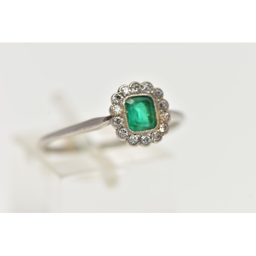 54 - A WHITE METAL, EMERALD AND DIAMOND CLUSTER RING, centering on an emerald cut emerald, in a milgrain ... 