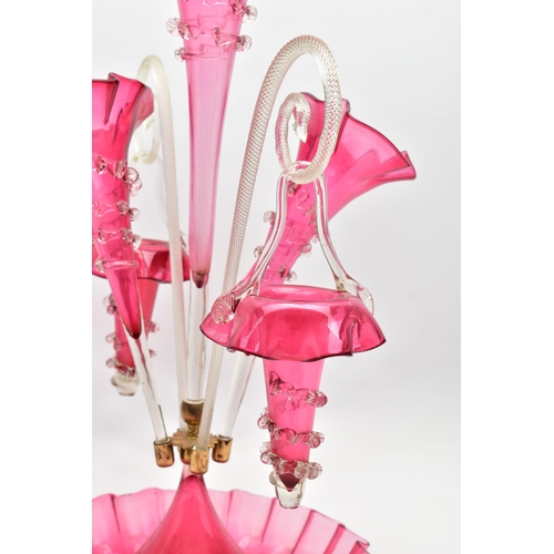 114 - A VICTORIAN CRANBERRY AND CLEAR GLASS EPERGNE, the central trumpet with trailing decoration, enclose... 