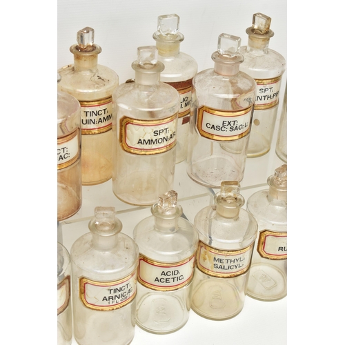 121 - A COLLECTION OF TWENTY FOUR CLEAR GLASS PHARMACY BOTTLES OF CYLINDRICAL FORM WITH STOPPERS, three ar... 