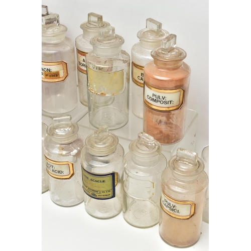 122 - A COLLECTION OF TWENTY CLEAR GLASS PHARMACY BOTTLES OF CYLINDRICAL FORM WITH STOPPERS, one is of a d... 