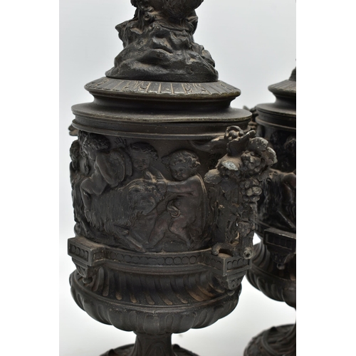 181 - A PAIR OF 19TH CENTURY BLACK PAINTED SPELTER TWIN HANDLED URNS AND COVERS, the covers cast with a pu... 