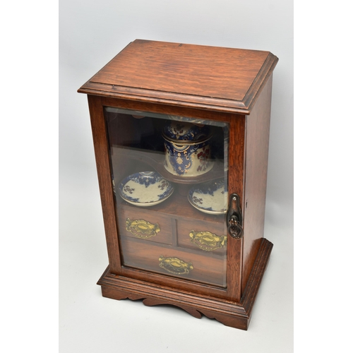 208 - A LATE VICTORIAN OAK CASED SMOKERS CABINET, the bevel edged glazed door opening to reveal a pipe rac... 