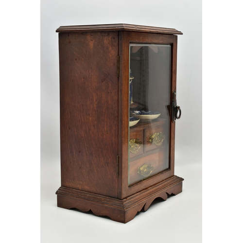 208 - A LATE VICTORIAN OAK CASED SMOKERS CABINET, the bevel edged glazed door opening to reveal a pipe rac... 