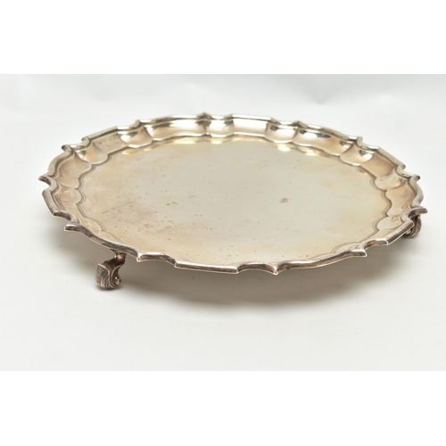 67 - A GEORGE V SILVER SALVER OF CIRCULAR FORM WITH PIE CRUST RIM, engraved narrow border, on three scrol... 