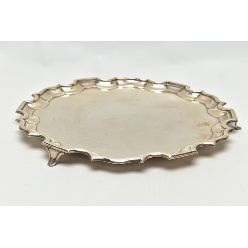 75 - A GEORGE V SILVER SALVER OF CIRCULAR FORM WITH PIE CRUST RIM, plain surface, on three short cabriole... 