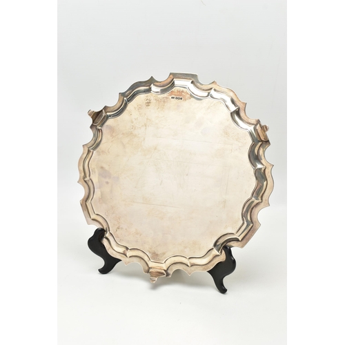 75 - A GEORGE V SILVER SALVER OF CIRCULAR FORM WITH PIE CRUST RIM, plain surface, on three short cabriole... 