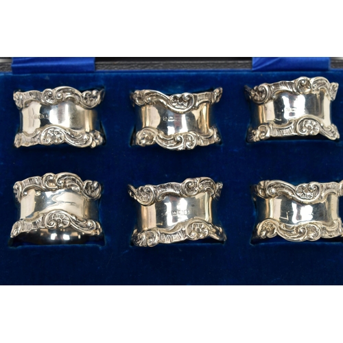 80 - A CASED SET OF SIX GEORGE V SILVER NAPKIN RINGS, of circular form cast with scrolled rims, maker's m... 