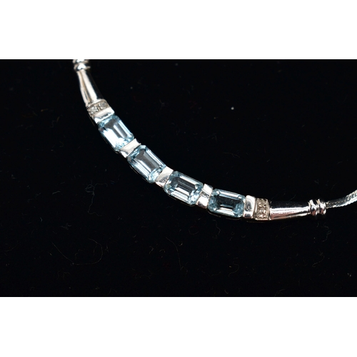 39 - A 9CT GOLD, TOPAZ NECKLACE, a solid white gold crecent shaped bar, set with four emerald cut blue to... 