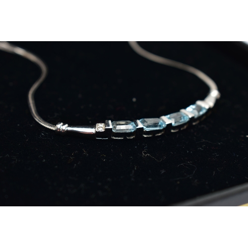 39 - A 9CT GOLD, TOPAZ NECKLACE, a solid white gold crecent shaped bar, set with four emerald cut blue to... 