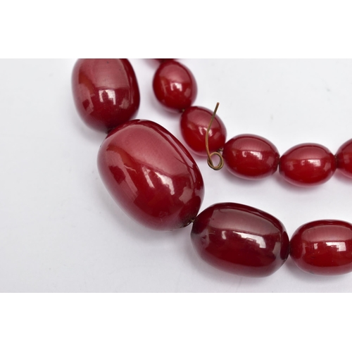 45 - A GRADUATING BAKELITE BEAD NECKLACE, oval cherry amber colour beads, graduating in size, largest mea... 