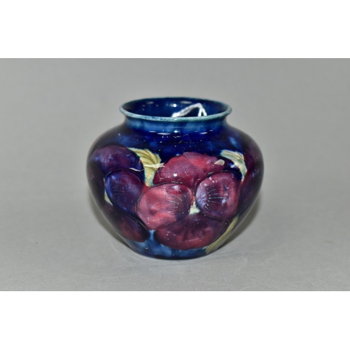 386 - A SMALL MOORCROFT POTTERY BALUSTER VASE, decorated with tube lined purple Pansy pattern on a dark bl... 