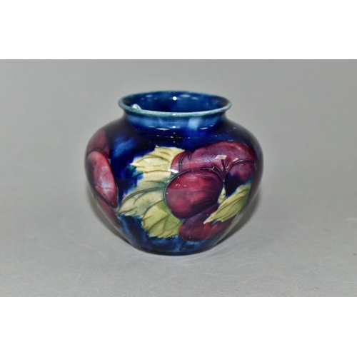 386 - A SMALL MOORCROFT POTTERY BALUSTER VASE, decorated with tube lined purple Pansy pattern on a dark bl... 