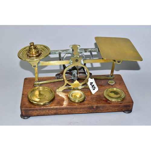 445 - A SET OF BRASS POSTAL SCALES WITH A COMPLETE SET OF BRASS WEIGHTS, mounted to a wooden plinth