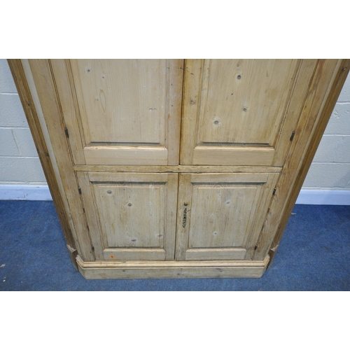 1312 - A LARGE VICTORIAN PINE PANELLED FOUR DOOR CORNER CUPBOARD, enclosing a blue painted interior, and th... 