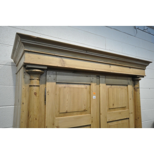 1315 - A FRENCH PINE WARDROBE, with an overhanging cornice, double panelled doors, flanked by half turned p... 