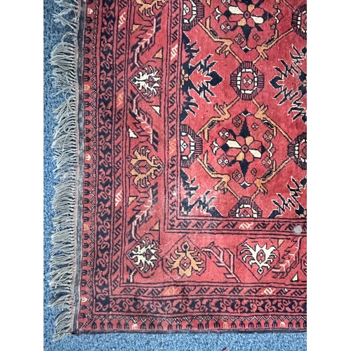 1365 - A LATE 19TH/EARLY 20TH CENTURY RUG, red field within a repeating geometric pattern, and multi strap ... 