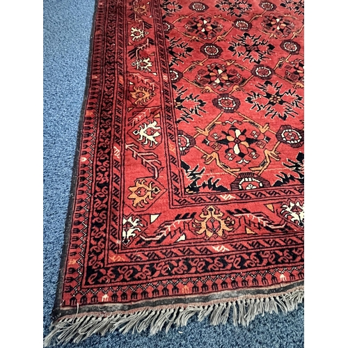 1365 - A LATE 19TH/EARLY 20TH CENTURY RUG, red field within a repeating geometric pattern, and multi strap ... 