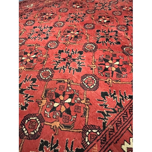 1365 - A LATE 19TH/EARLY 20TH CENTURY RUG, red field within a repeating geometric pattern, and multi strap ... 