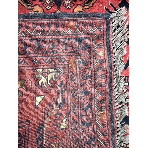 1365 - A LATE 19TH/EARLY 20TH CENTURY RUG, red field within a repeating geometric pattern, and multi strap ... 