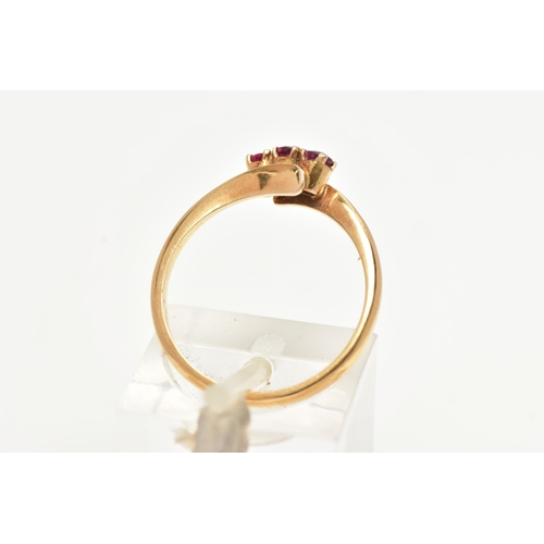 15 - A THREE STONE RUBY RING, three circular cut rubies prong set in yellow metal, leading on to a bypass... 