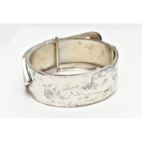 6 - A SILVER HINGED BANGLE, in the form of a belt and buckle, decorated with a floral pattern, hallmarke... 