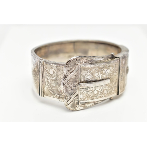 7 - A SILVER HINGED BANGLE, in the form of belt and buckle, decorated with a floral pattern, hallmarked ... 