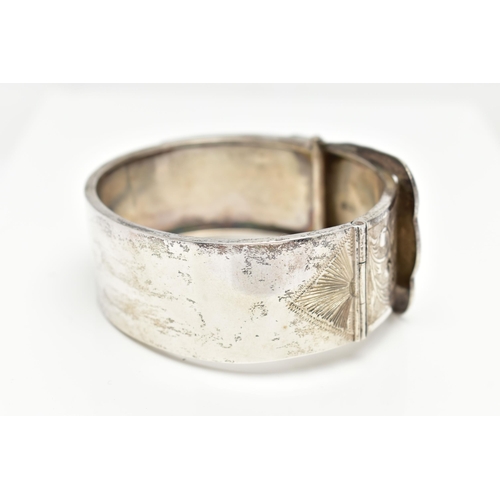 7 - A SILVER HINGED BANGLE, in the form of belt and buckle, decorated with a floral pattern, hallmarked ... 