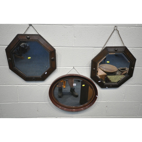 1243 - FIVE VARIOUS WALL MIRRORS, comprising four sized oak octagonal wall mirrors, largest 80cm x 52cm, an... 