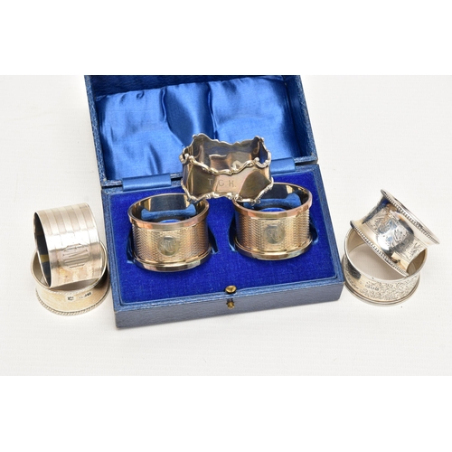 155 - A PAIR OF CASED GEORGE V SILVER CIRCULAR NAPKIN RINGS AND FIVE OTHER SILVER NAPKIN RINGS, the cased ... 