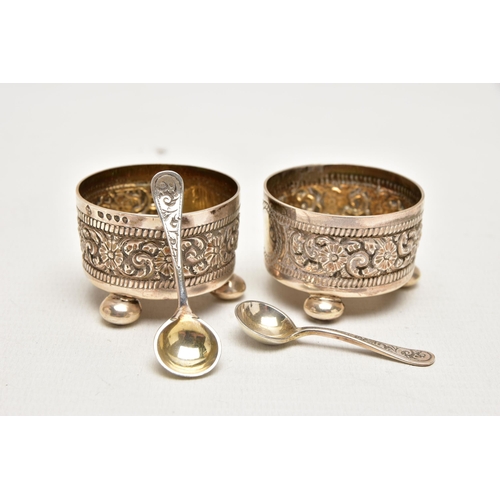 182 - A PAIR OF LATE VICTORIAN SILVER SALTS, each decorated with an embossed floral pattern with vacant ca... 