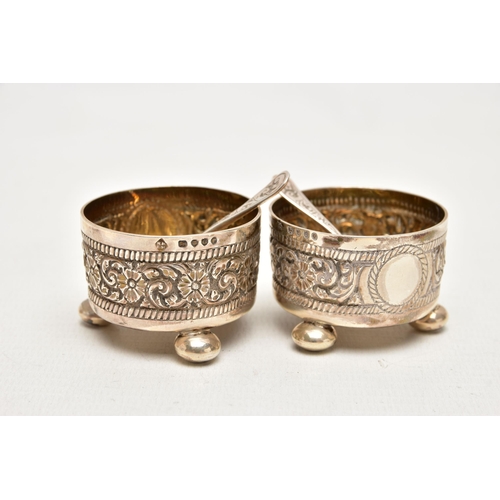 182 - A PAIR OF LATE VICTORIAN SILVER SALTS, each decorated with an embossed floral pattern with vacant ca... 