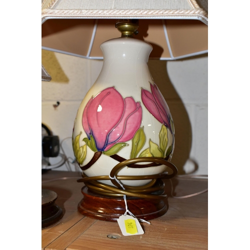 374 - A PAIR OF MOORCROFT POTTERY TABLE LAMPS, comprising two pink magnolia on cream ground lamp bases wit... 