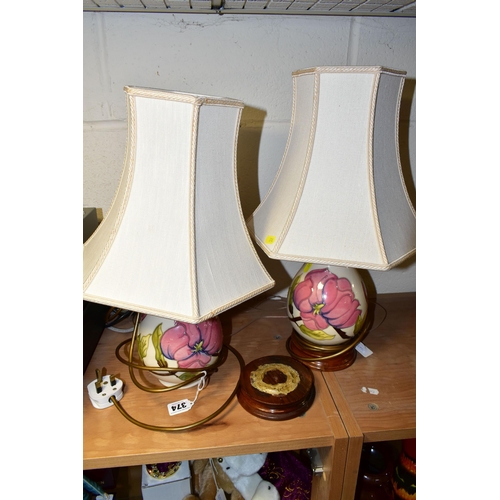 374 - A PAIR OF MOORCROFT POTTERY TABLE LAMPS, comprising two pink magnolia on cream ground lamp bases wit... 