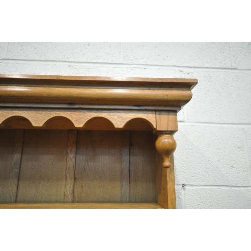 1202 - A REPRODUCTION OAK DRESSER, the top being a three tier plate rack, on a base with two deep drawers, ... 