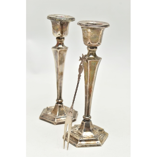 152 - A PAIR OF SILVER CANDLESTICKS AND A TWO PRONG FORK, the candlesticks of a tapered hexagonal form, on... 