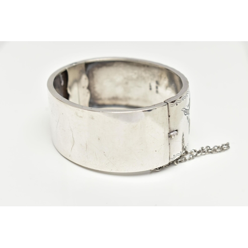 64 - A SILVER HINGED BANGLE,  a wide bangle decorated with a yellow and rose metal foliage etched pattern... 