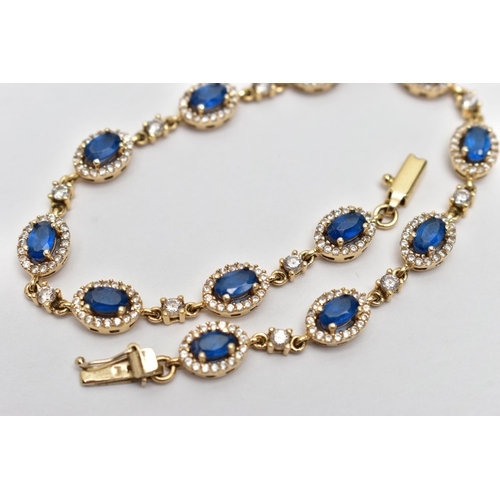 67 - A YELLOW METAL GEM SET BRACELET, comprised of twelve oval cut synthetic blue spinel, each set with a... 