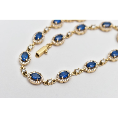 67 - A YELLOW METAL GEM SET BRACELET, comprised of twelve oval cut synthetic blue spinel, each set with a... 